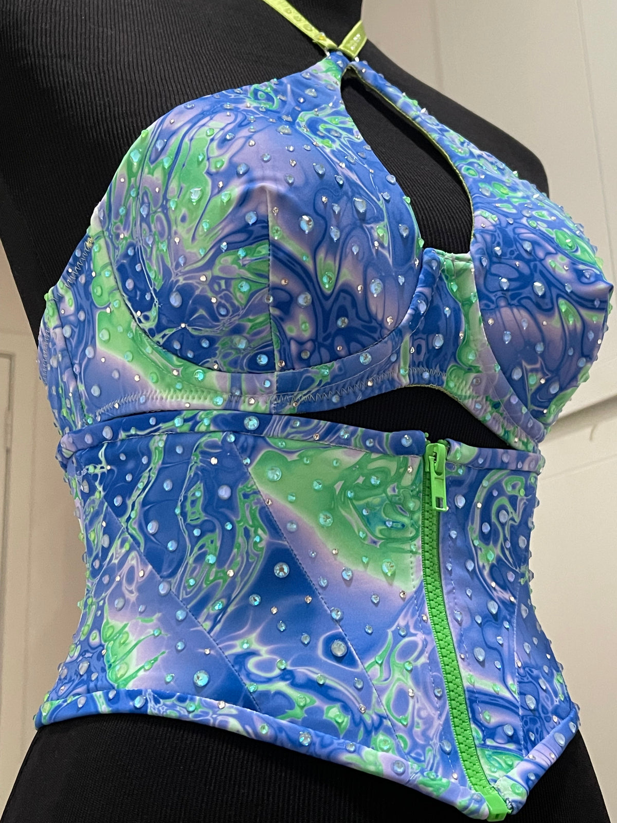 Blue and green patterned stage costume bra and waist cincher corset with hand placed Looking Glass Gems rhinestones on a black mannequin