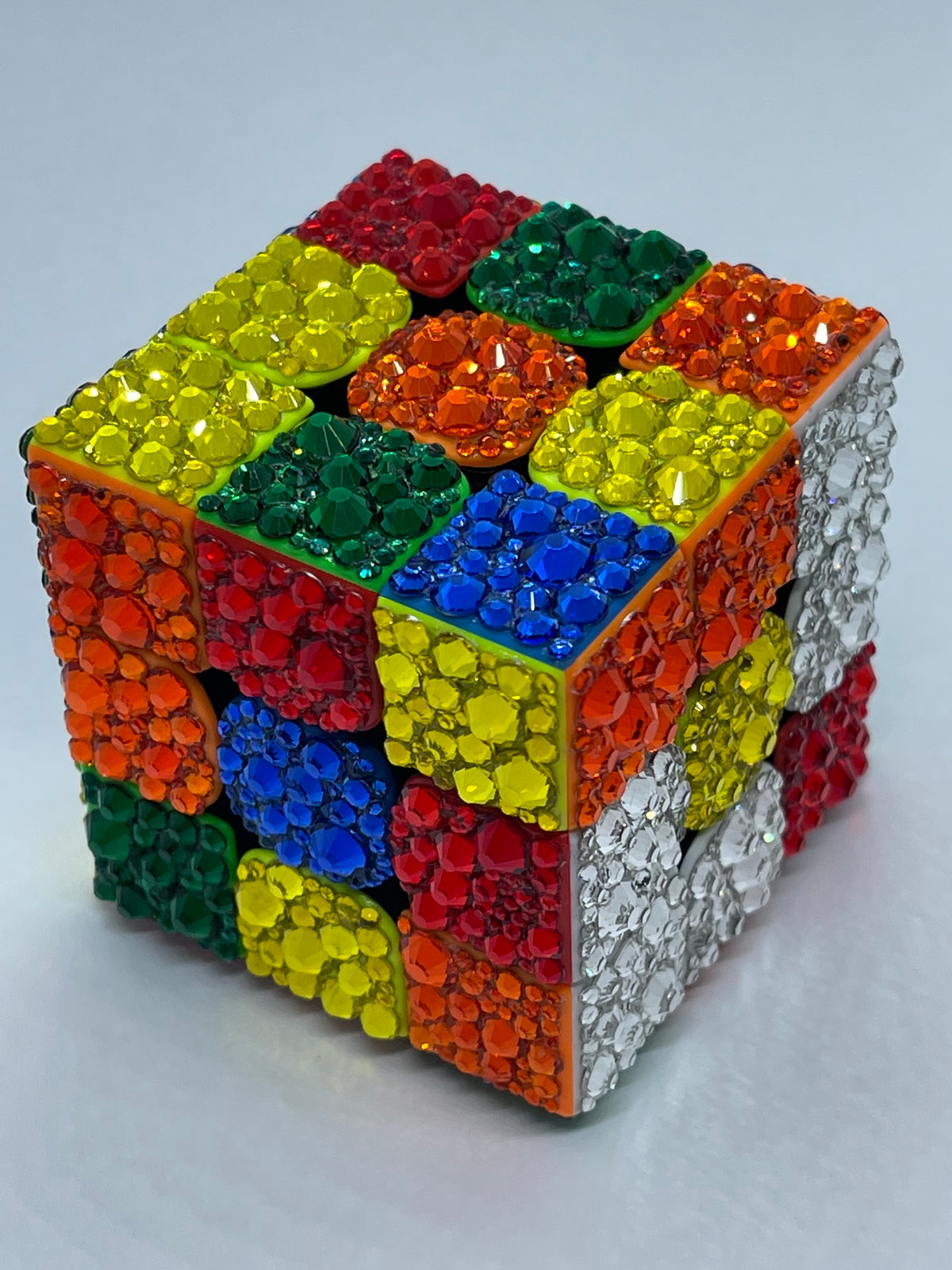 Colorful Rubik's Cube puzzle cube with hand lace Looking Glass Gems rhinestones on a white background